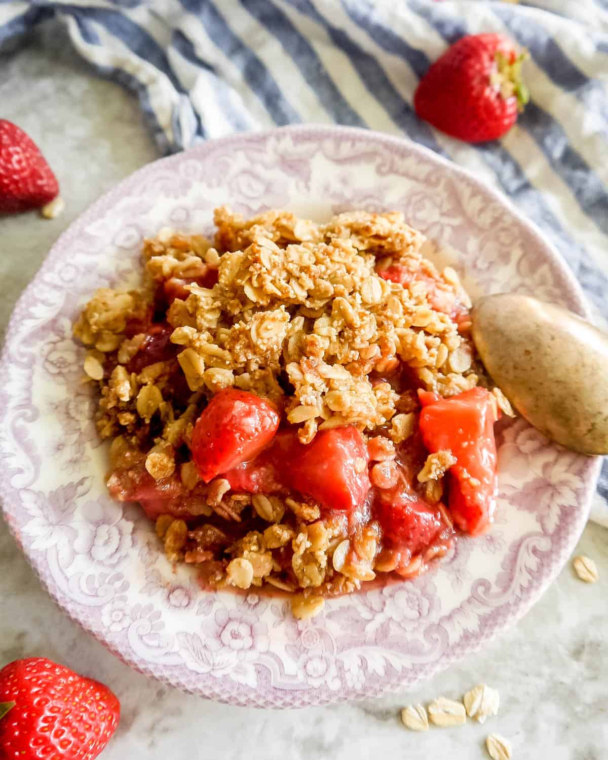 A plate full of strawberry crisp, with a spoon on the plate.
