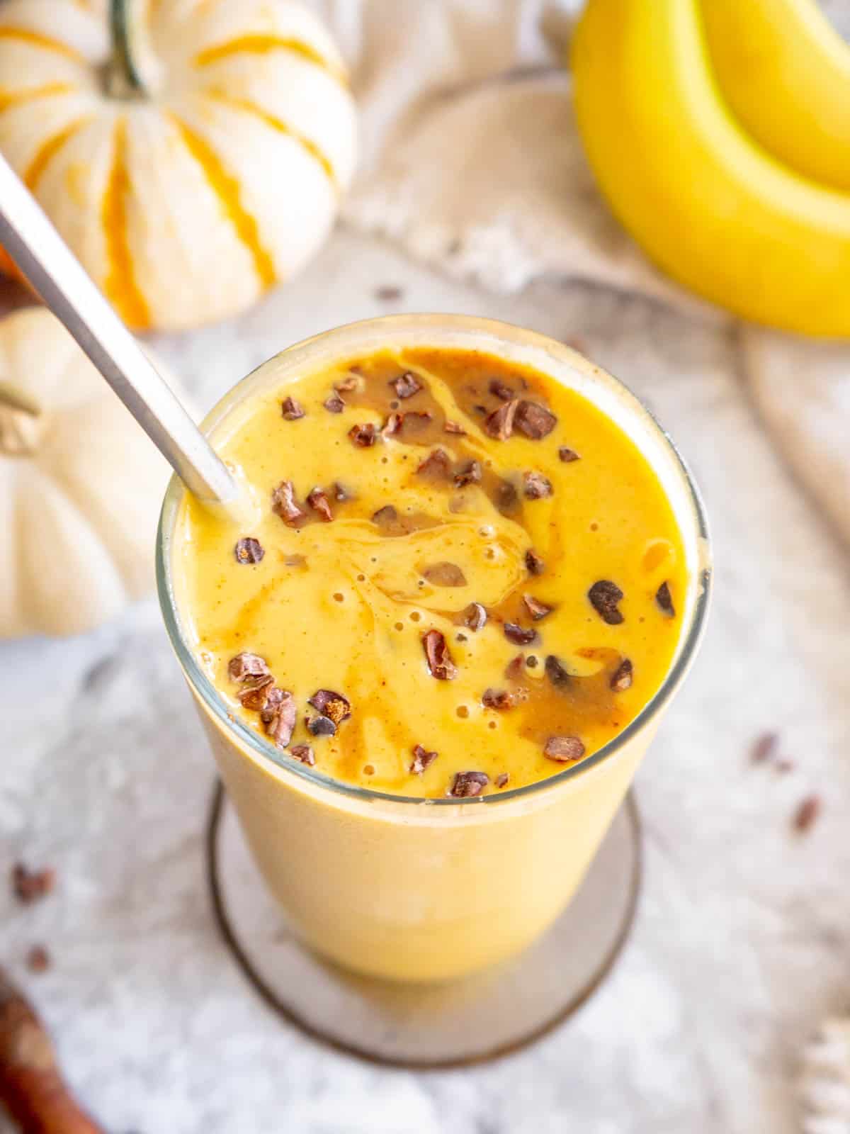 Pumpkin spice smoothie with banana mixed together with cacao nibs inside.