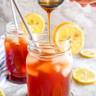 Maple syrup being poured into a glass of healthy sweet tea.
