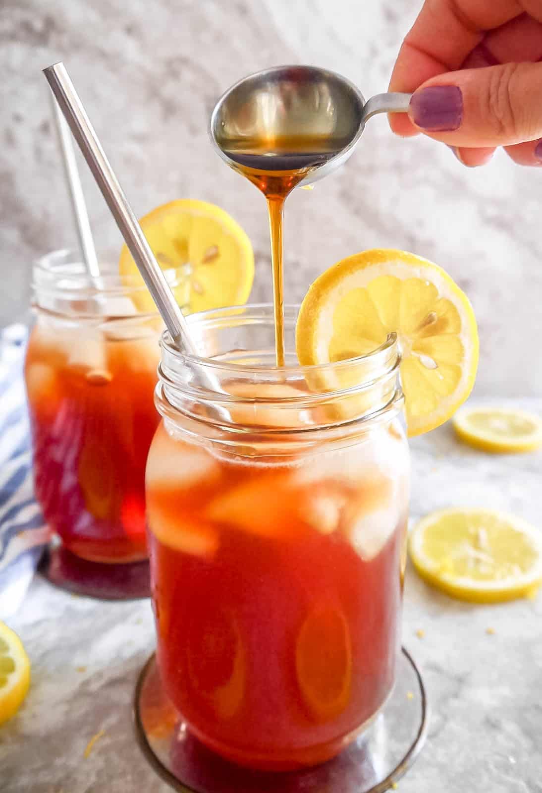 Maple syrup being poured into a glass of healthy sweet tea.