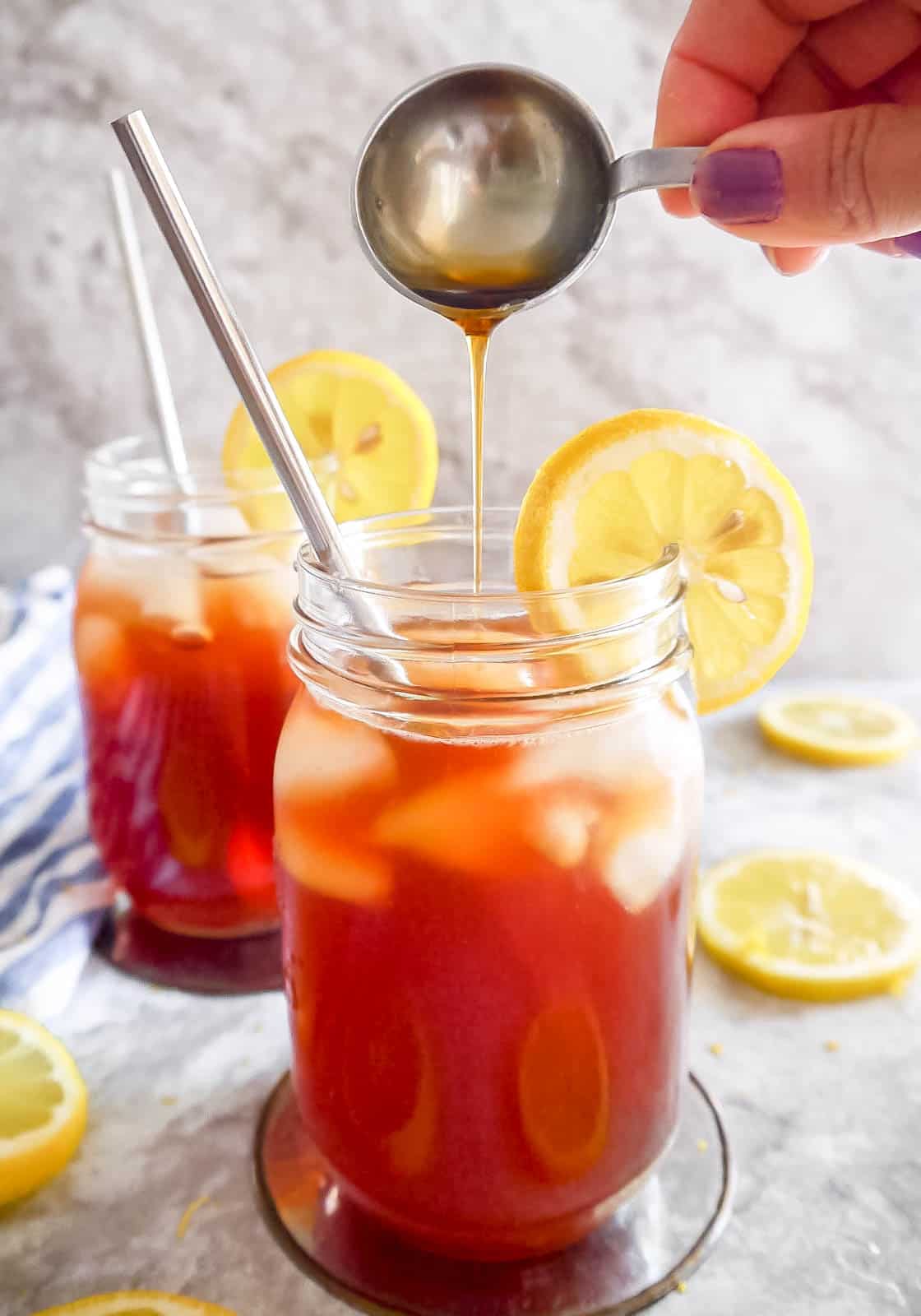 Healthy sweet tea in two cups with maple syrup being poured into a cup.