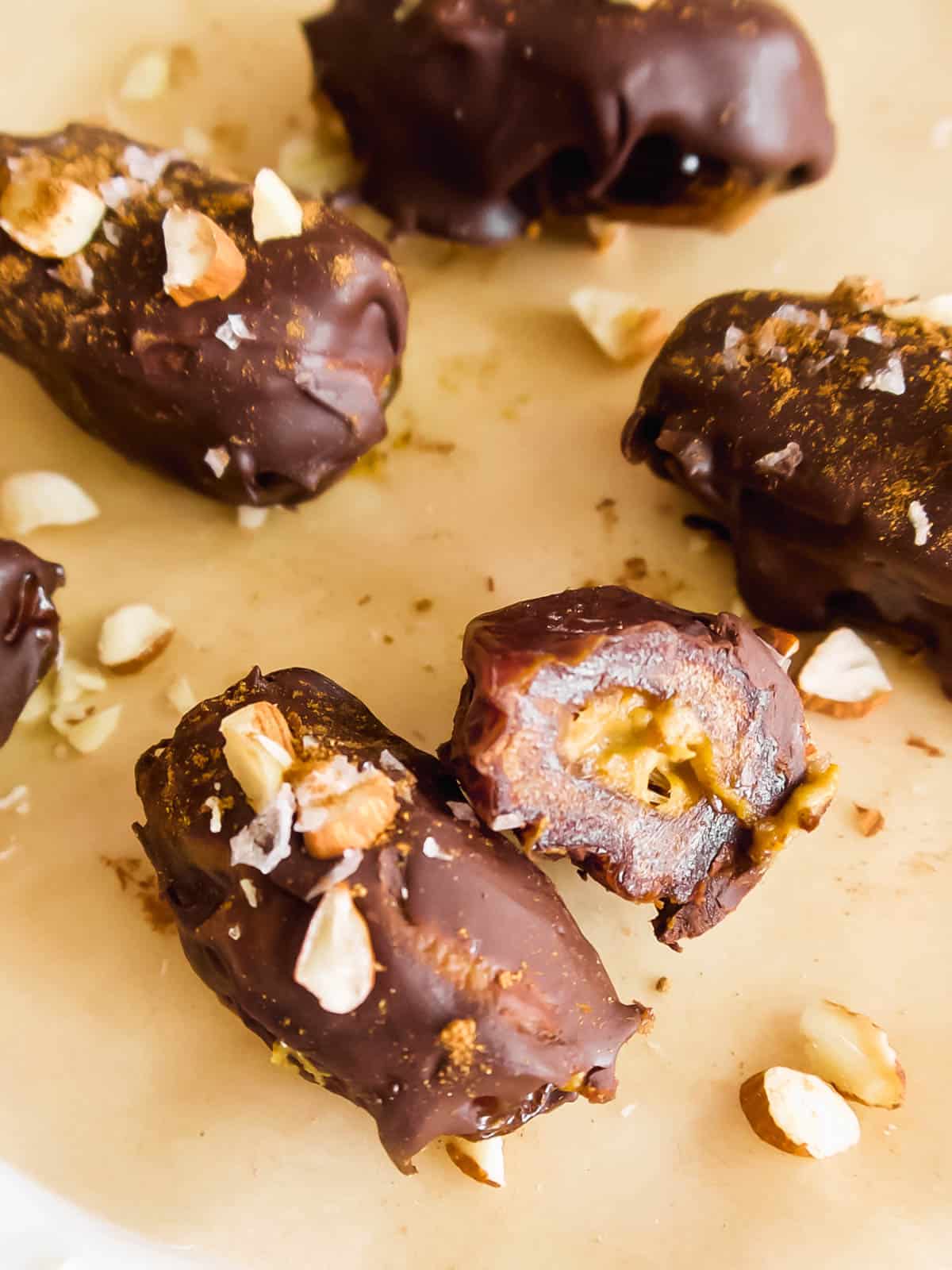 Pumpkin dates cut in half surrounded by crushed almonds.