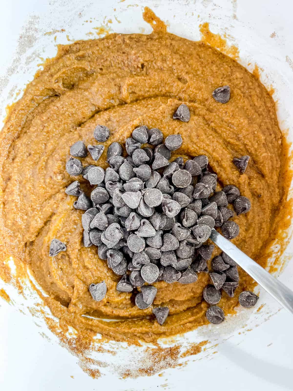 Chocolate chips added to paleo pumpkin chocolate chip muffins batter.