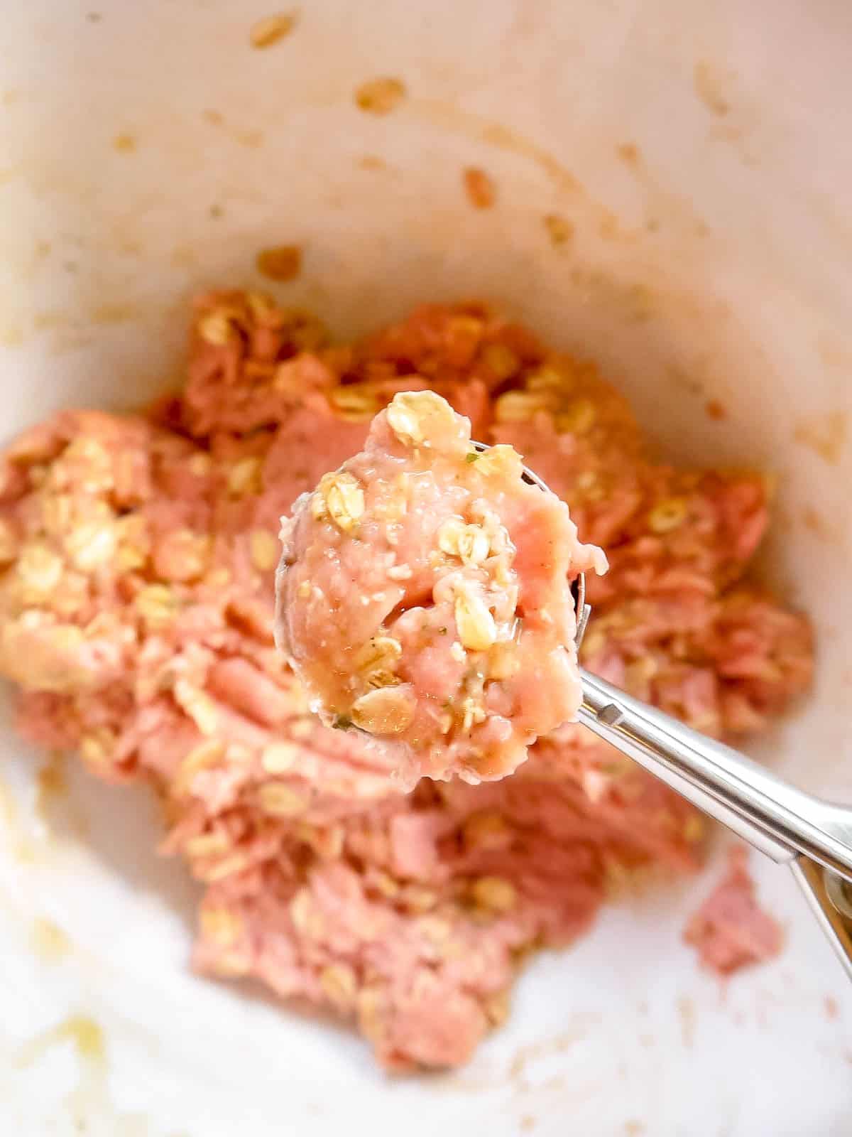 Meatball mixture scooped out in a cookie scoop.
