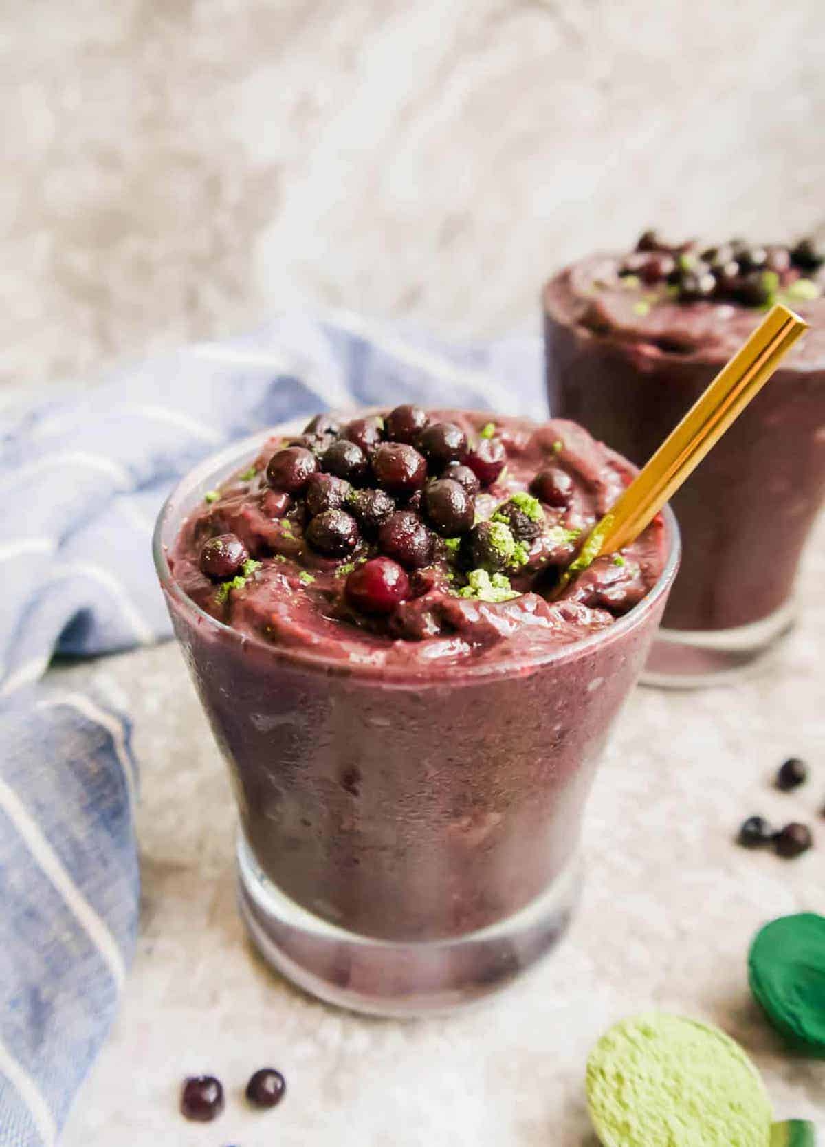 Photo of wild blueberry smoothie in two cups with wild blueberries on top.