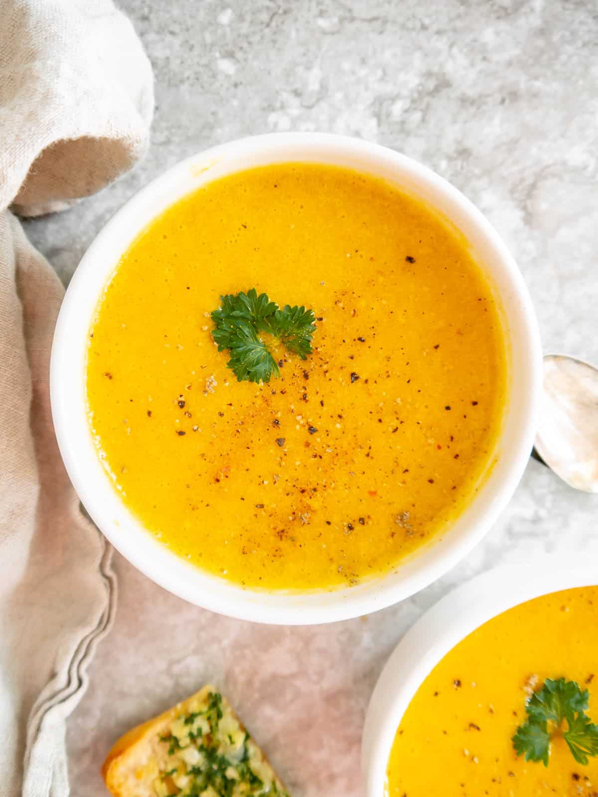 Roasted butternut squash soup in two bowls with parsley on top.