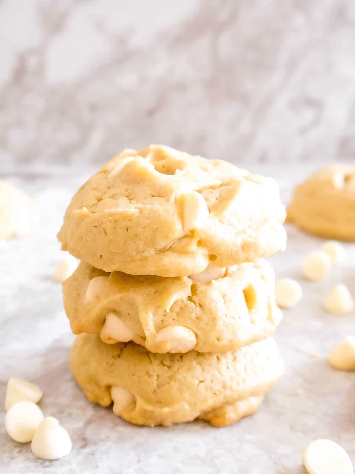 A stack of 3 white chocolate chip cookies.