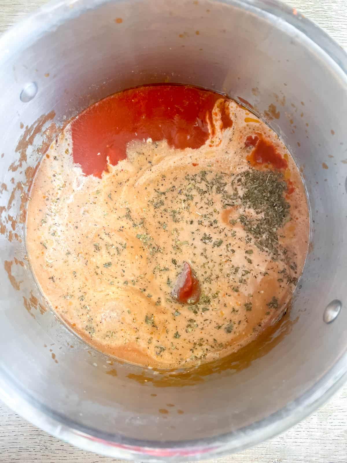 Heavy cream, bone broth, and tomato sauce added to a pan.