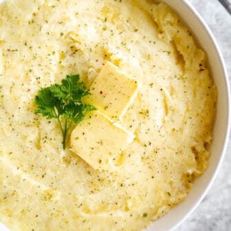 Mashed potatoes cottage cheese in a large bowl with butter on top.