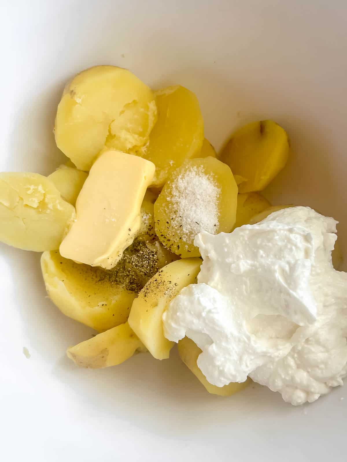 The potatoes, cottage cheese, butter, salt and pepper in a large bowl.