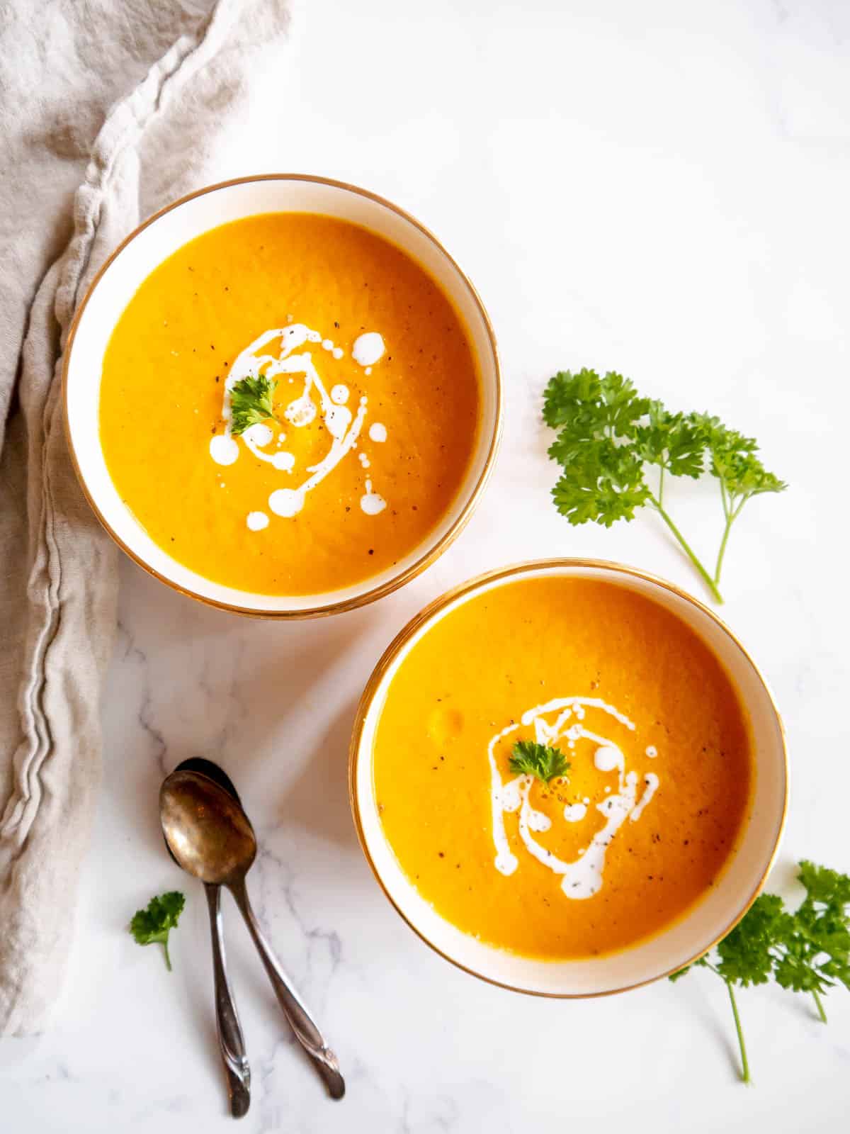 Roasted butternut squash and carrot soup in two bowls.