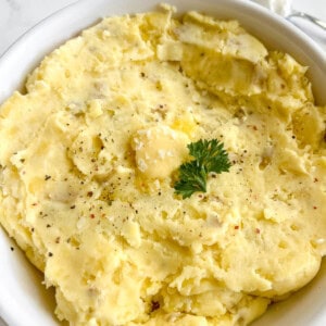 Greek yogurt mashed potatoes in a large bowl with butter melting on top.