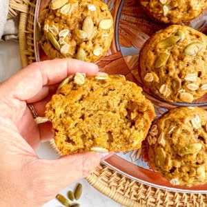 Pumpkin oat muffin sliced in half held in hands.