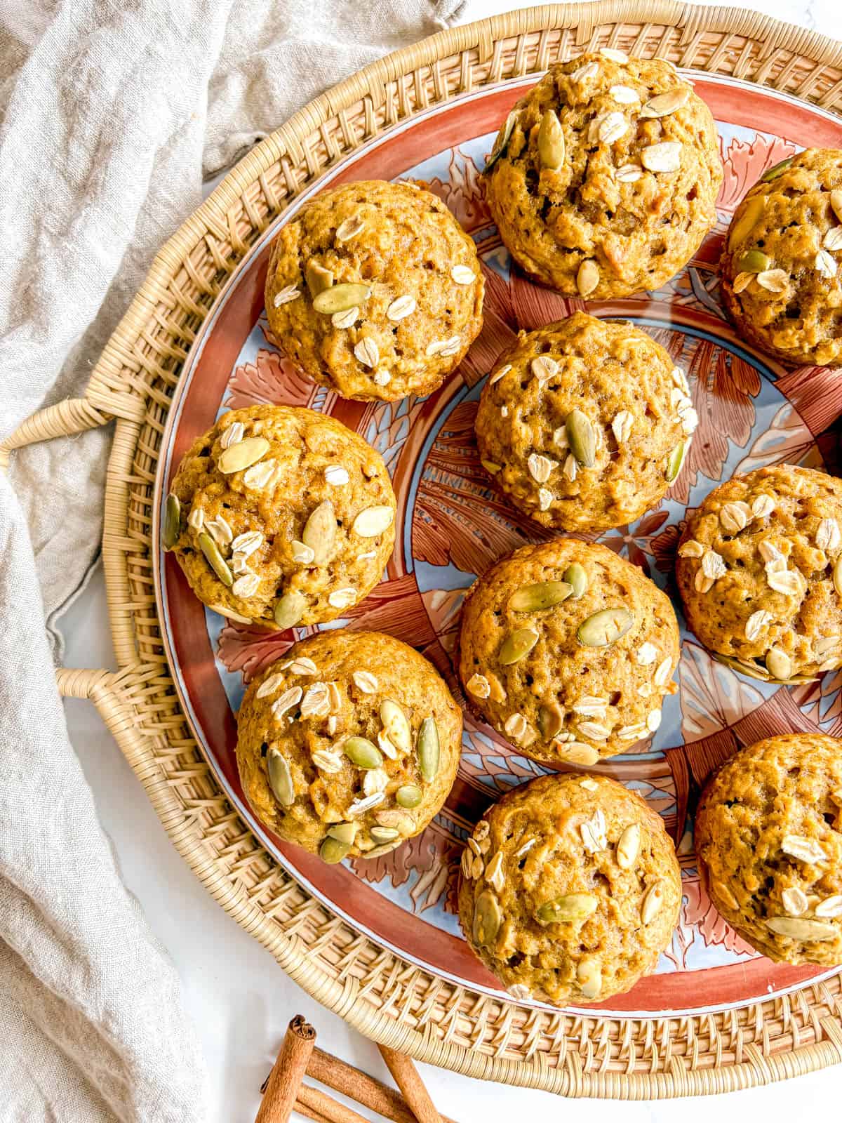 Dairy-free pumpkin muffins on a plate topped in oats and pumpkin seeds.