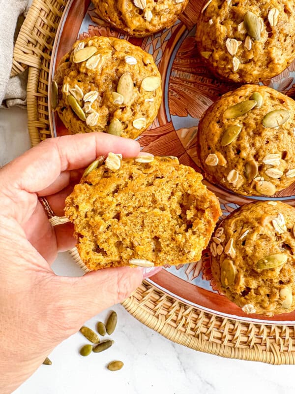 Pumpkin oat muffin sliced in half held in hands.