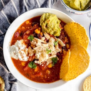 Crockpot turkey chili in a bowl with guac, cheese and greek yogurt on top.