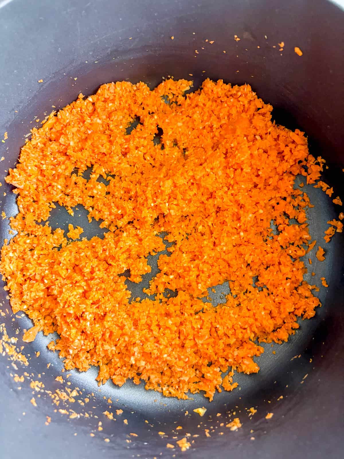 Sauteeing garlic and carrots in a pan.