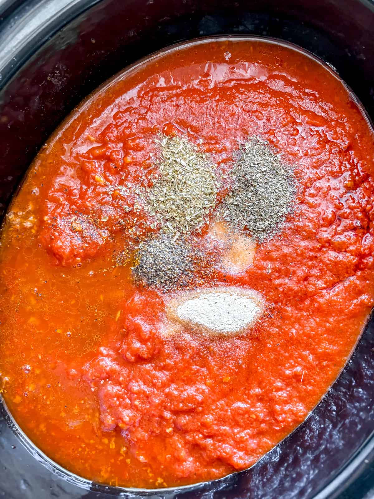 All of the crockpot spaghetti and meat sauce ingredients in a slow cooker.