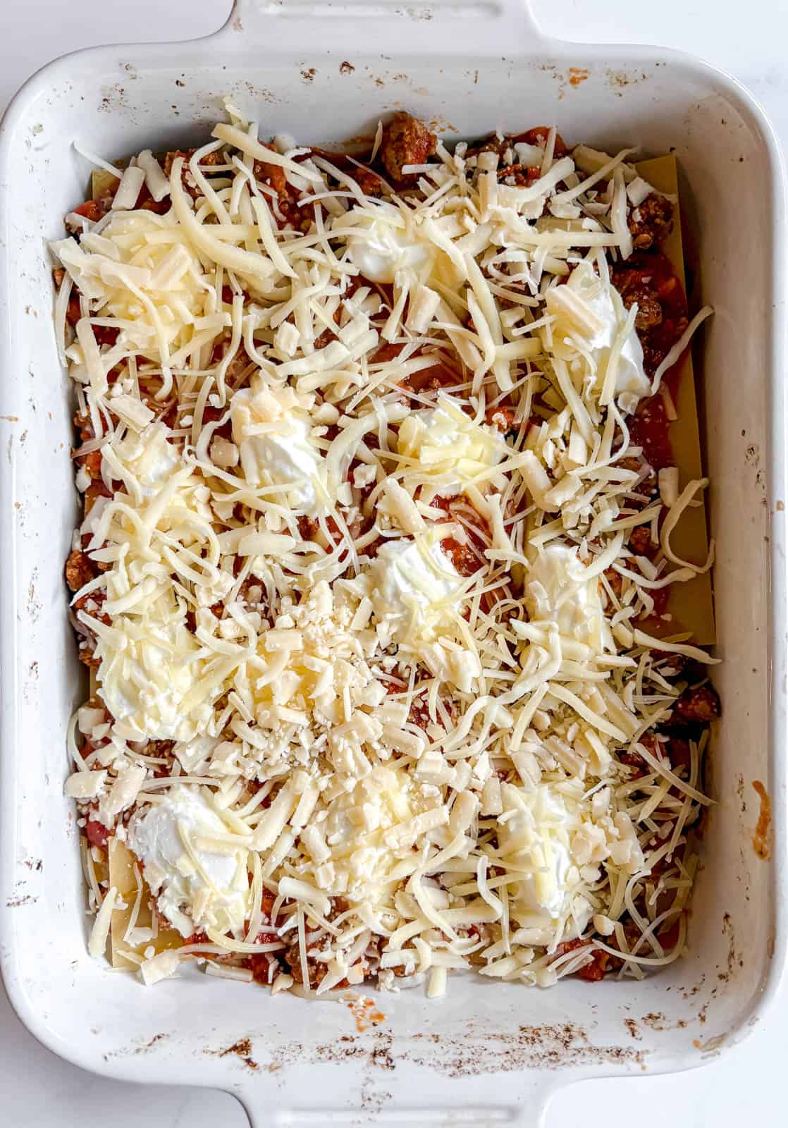 Shredded cheese added to the lasagna layer.