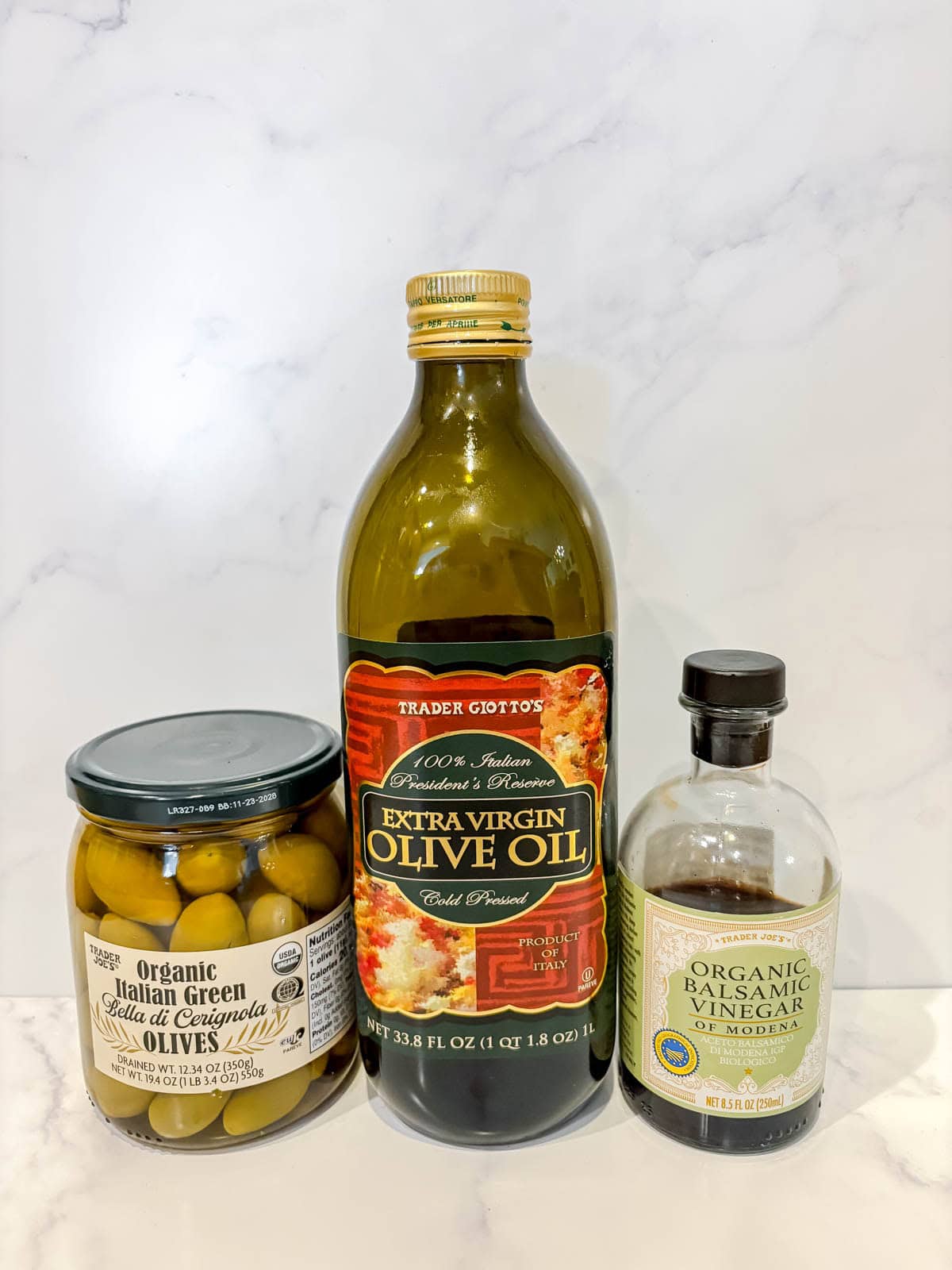 Ingredients needed to make warm green olives in balsamic vinegar and olive oil.