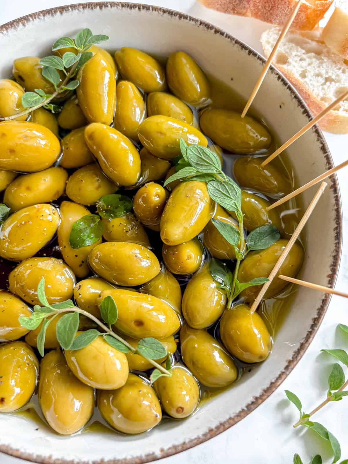 Warm Green Olives in Balsamic Vinegar and Olive oil in a bowl with toothpicks.