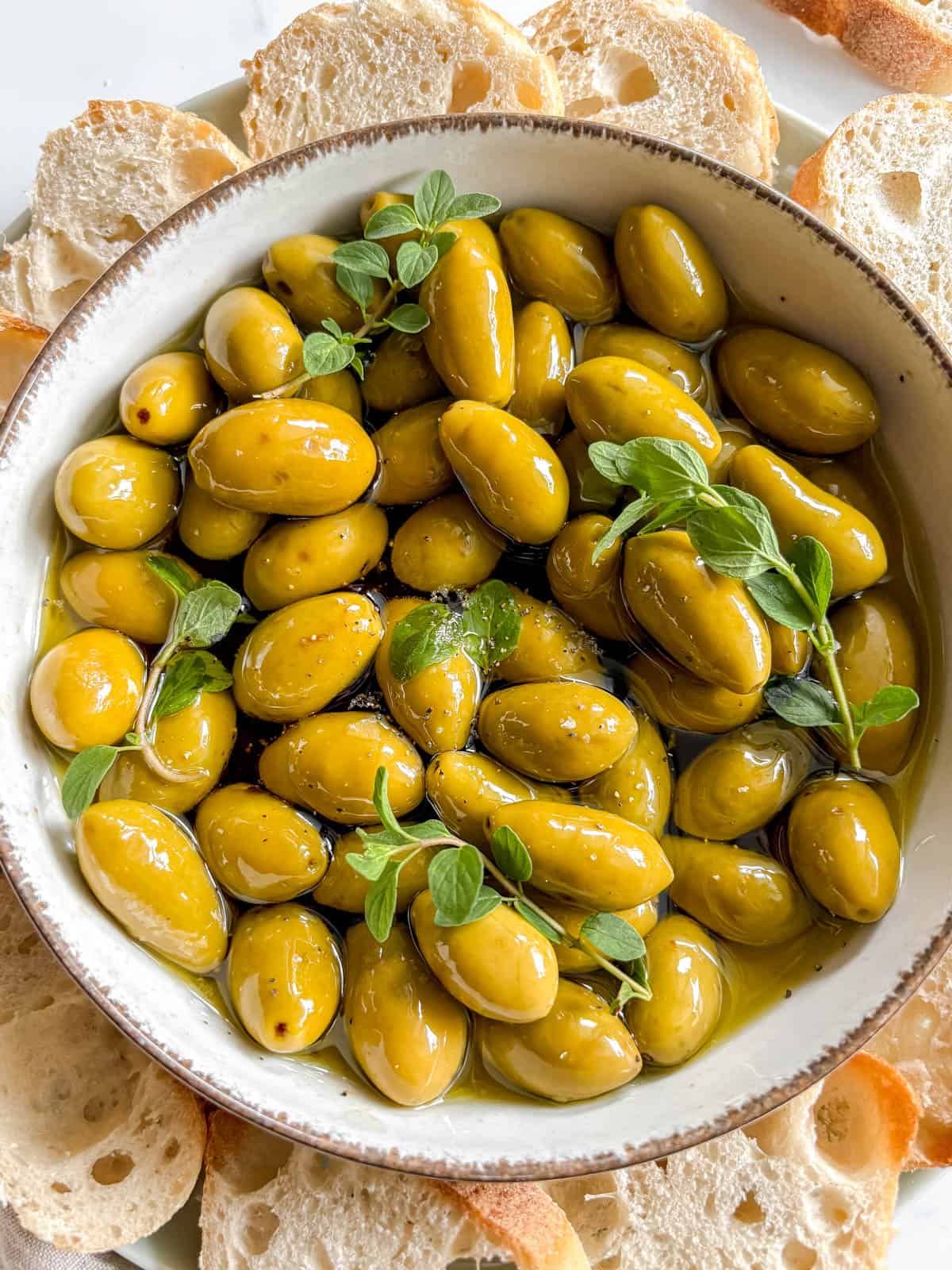 Salt, pepper, and fresh oregano added to the green olives.