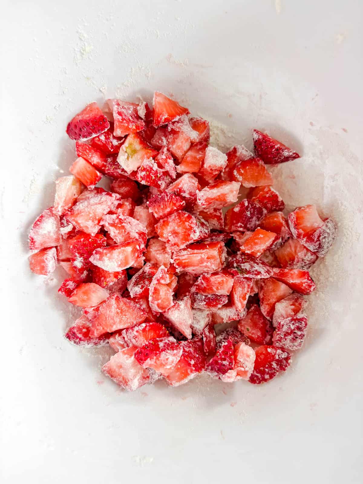 Chopped strawberries in a bowl with flour on top.