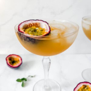 Passion fruit cocktail in a glass with half a passion fruit in the glass.