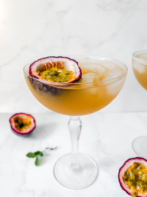 Passion fruit cocktail in a glass with half a passion fruit in the glass.