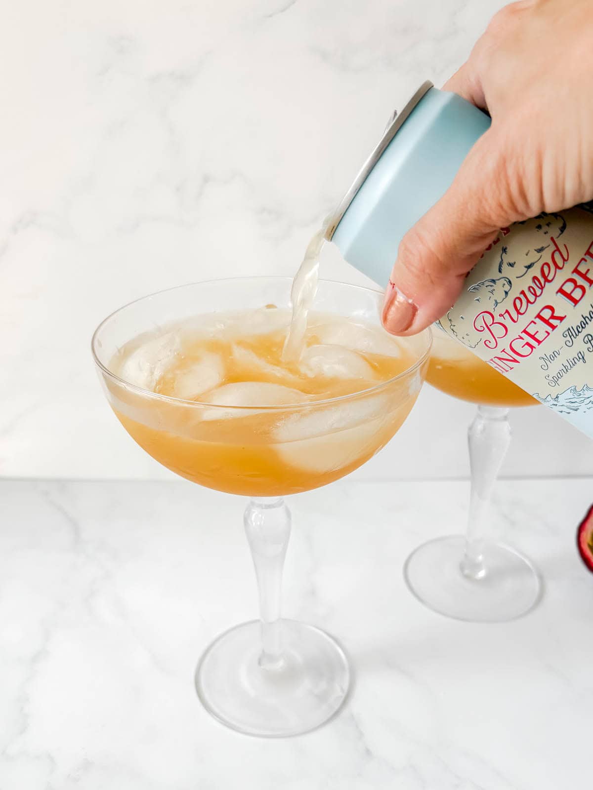 Pouring ginger beer on top of the drink.