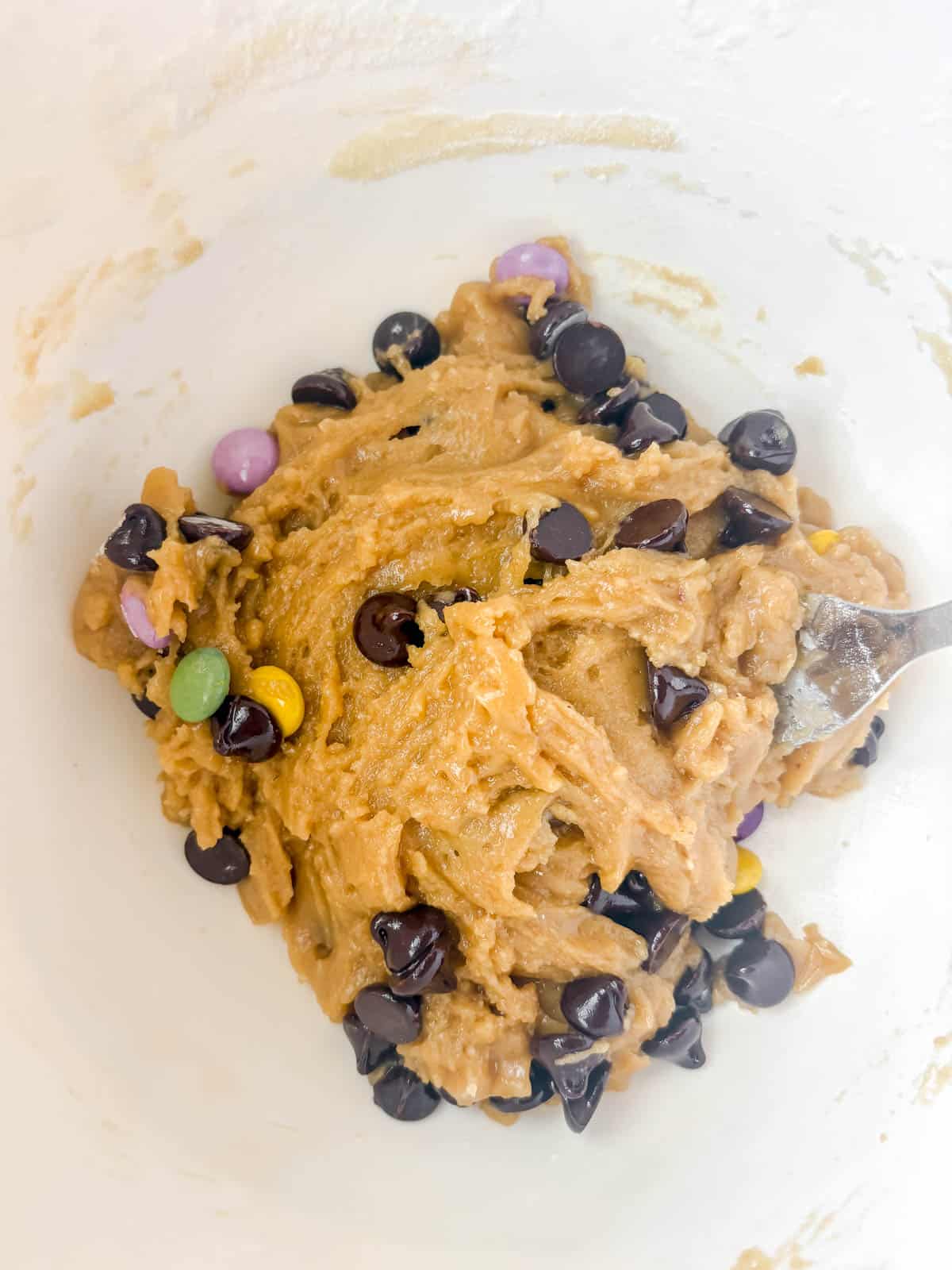 Chocolate chips added to the cookie dough in the bowl.