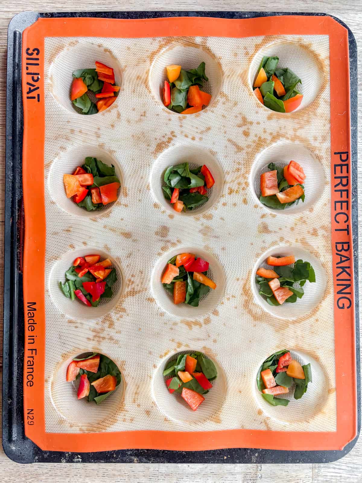 Red pepper and spinach in muffin tins.