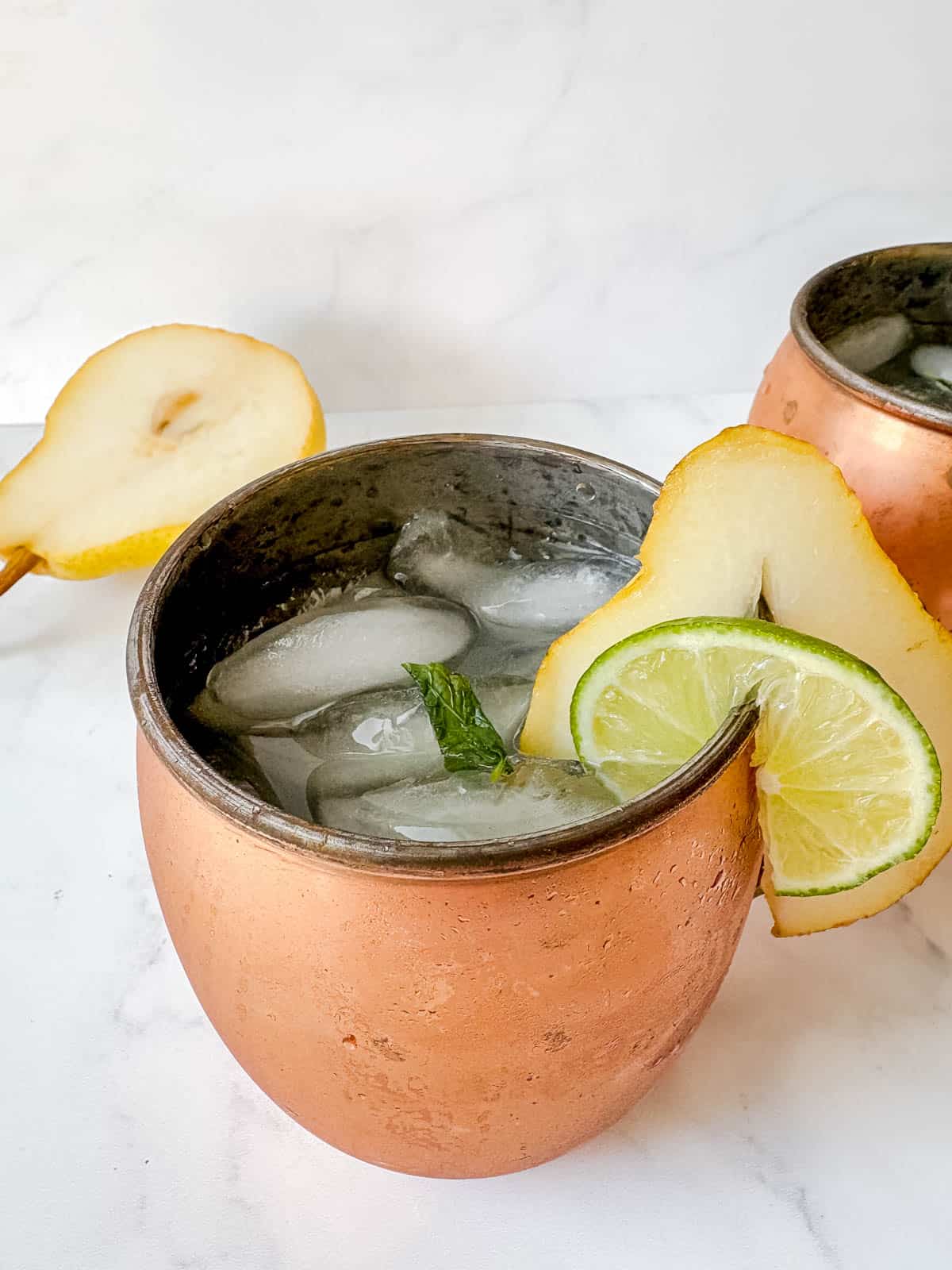 A fresh zesty pear gingerbeer cocktail in a moscow mule copper cup.