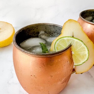 Pear Vodka Cocktail in a moscow mule cup with a sliced pear on the edge of the glass.