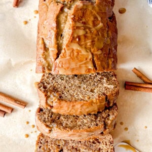 Maple banana bread with maple glaze sliced on a board.