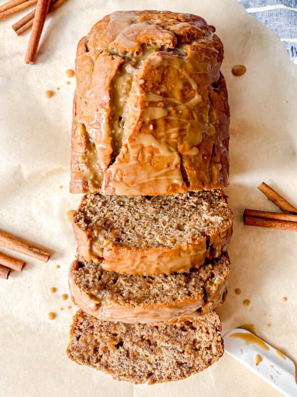 Maple banana bread with maple glaze sliced on a board.