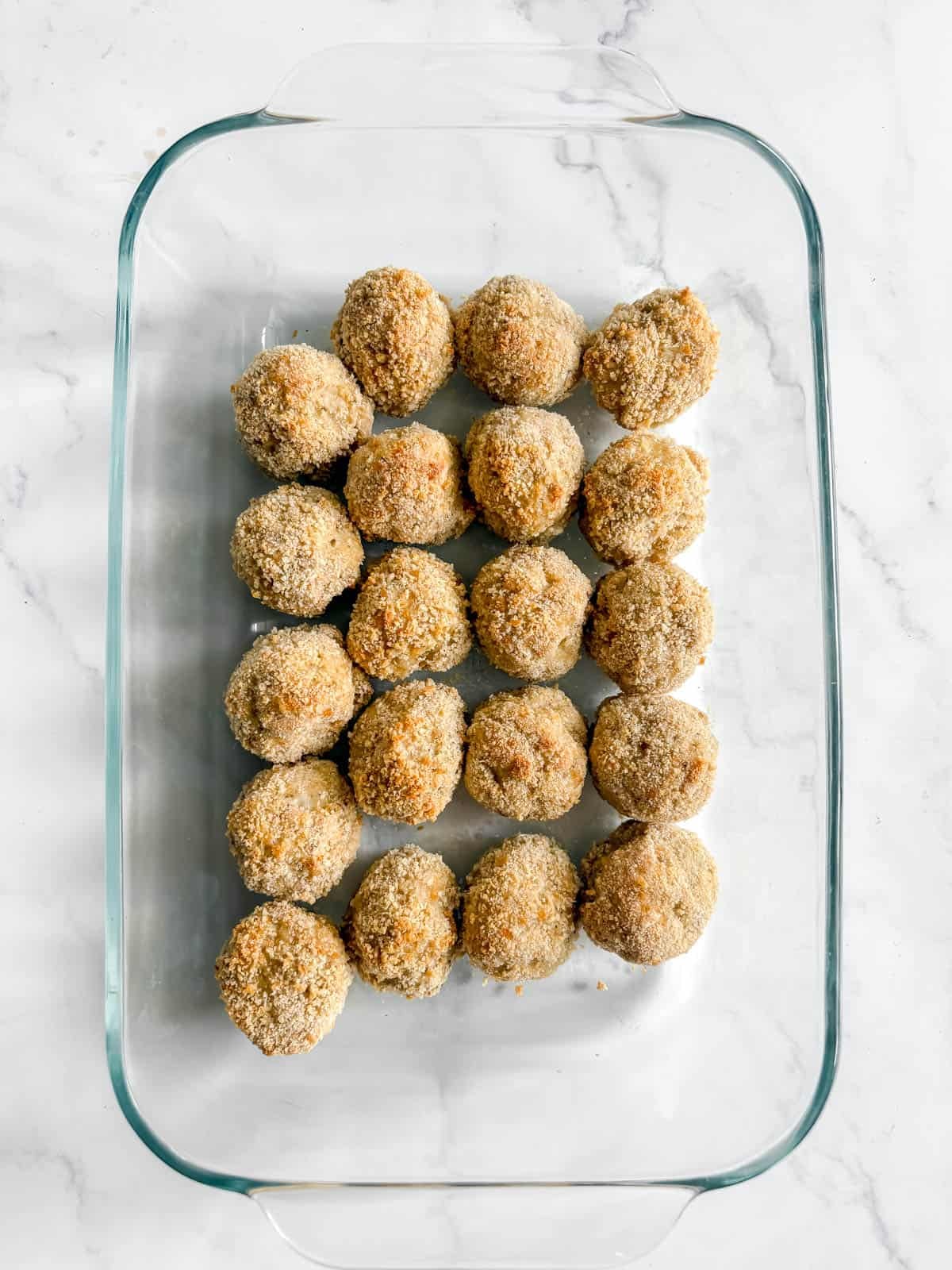 Chicken parmesan meatballs in a baking dish.