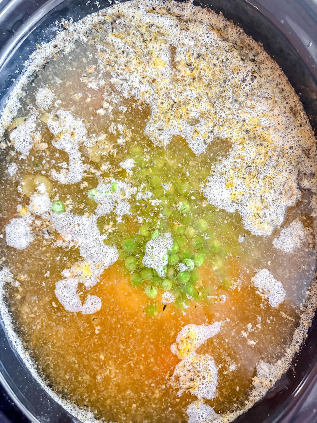 Peas added to slow cooker for chicken soup.