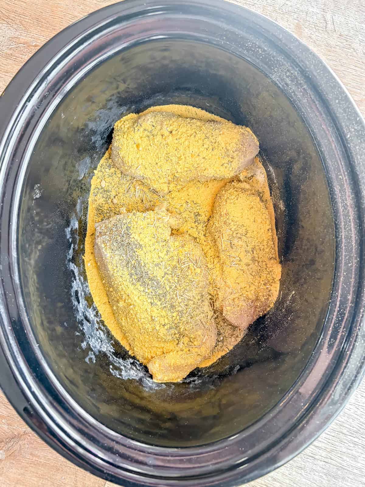 Chicken and spices in a crockpot.